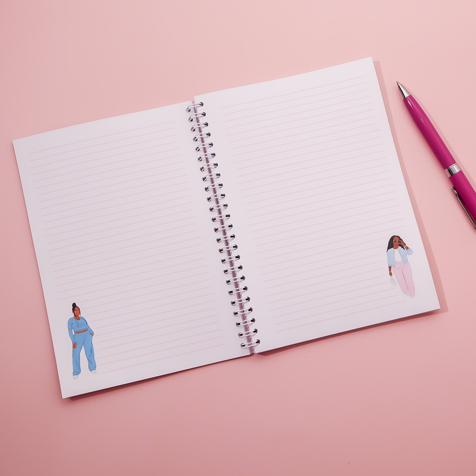 Open notebook with lined pages featuring illustrations of women on a pink background, accompanied by a pink pen.
